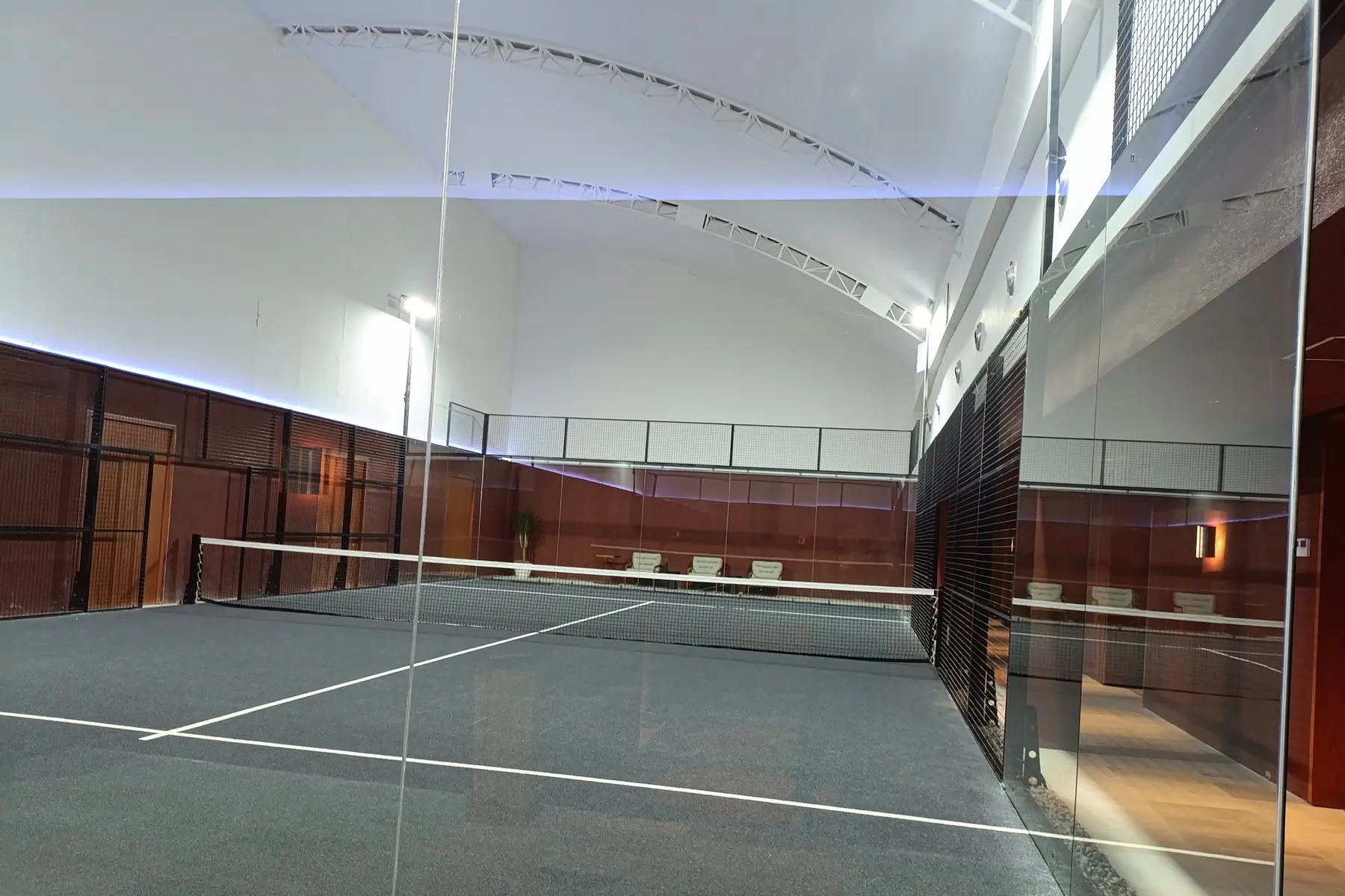 Padel court through the glass, with a lounge along the side