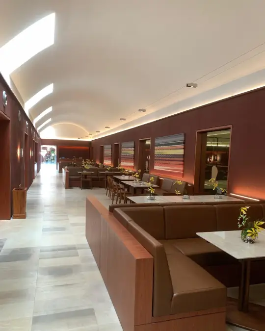 Long restaurant hall with leather booths under an arched ceiling