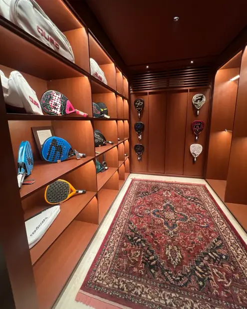 Shelves of padel rackets above a Persian rug